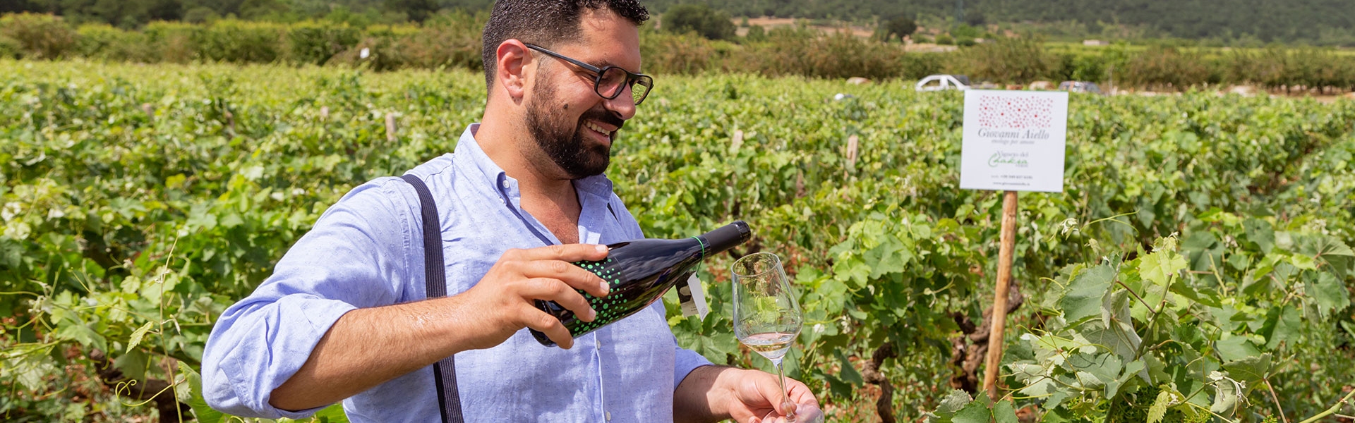 Giovanni Aiello pouring Chakra Verde wine while being in his vines in Puglia